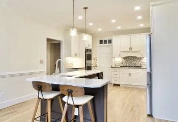 Contrasting kitchen island with glass pendants, prep sink, and seating