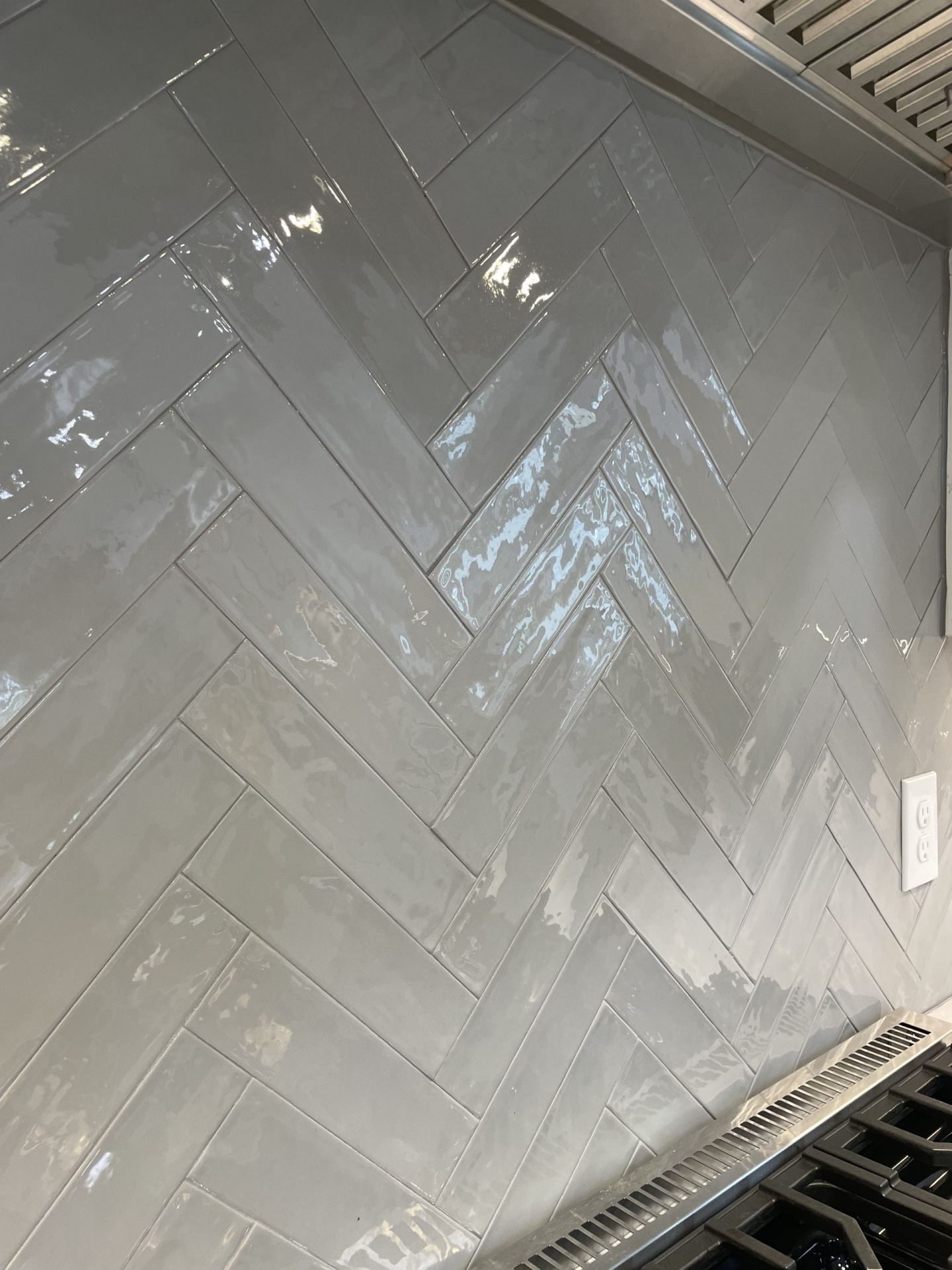 Herringbone gray glazed tile backsplash