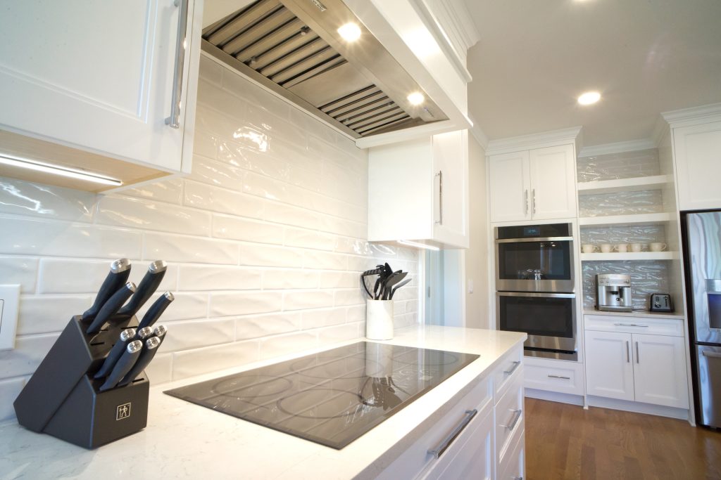 glass top oven and extra large range hood in white kitchen remodel